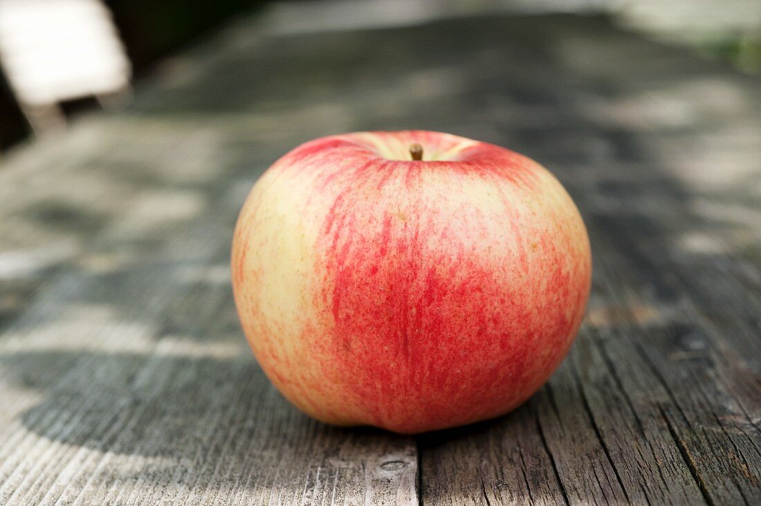 Ein Apfel auf Holztisch im Garten