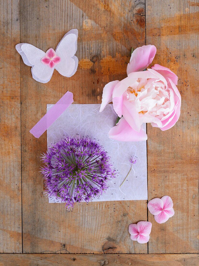 Flowers and paper butterfly on wooden surface