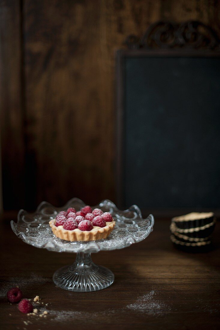 Small raspberry tart on a glass cake stand