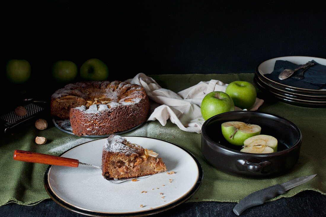 Apfelkuchen, angeschnitten, mit Stück auf Teller