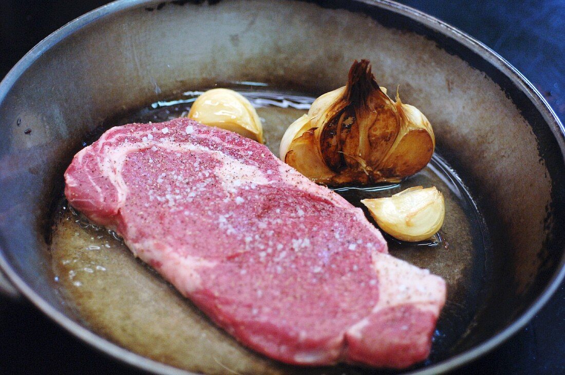 Angus beef steak with garlic in a frying pan