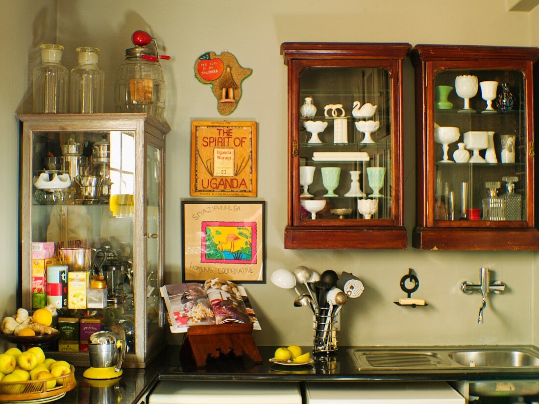 Collection of antique crockery in antique display cabinets on wall above kitchen counter in corner