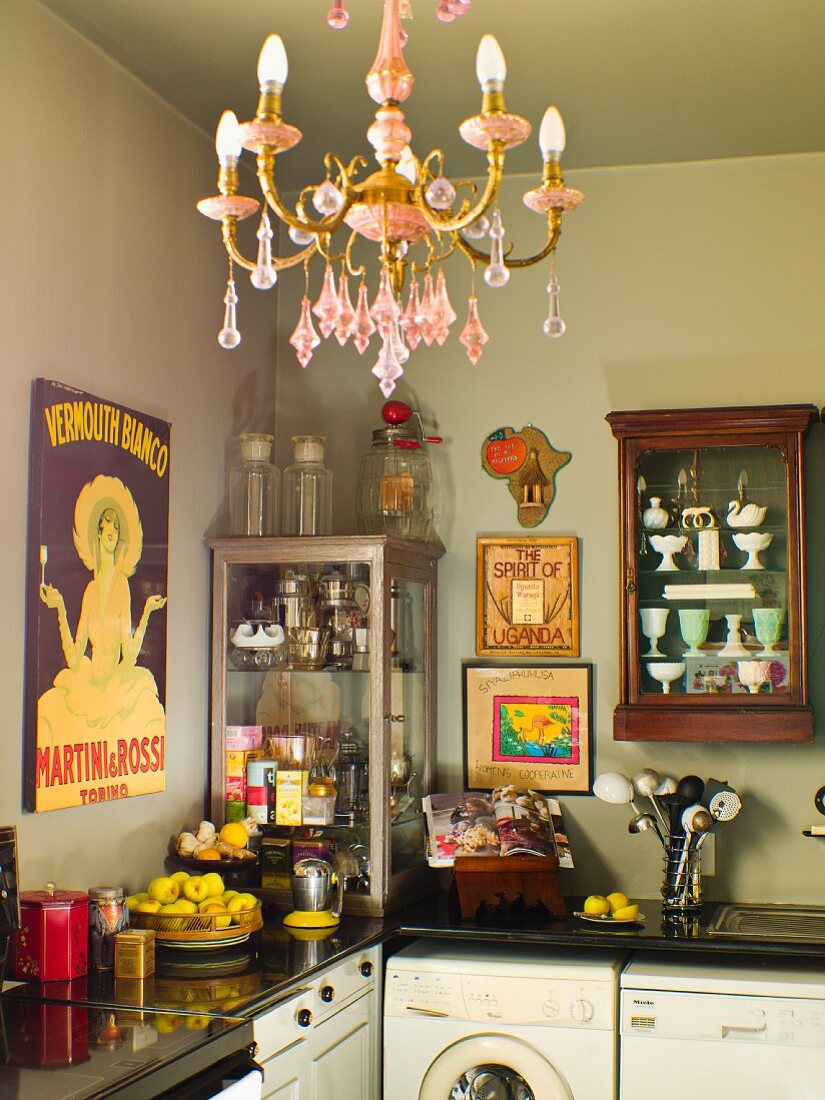 Corner of kitchen with antique crockery in display cabinets above worksurface; chandelier with pink crystal ornaments in foreground