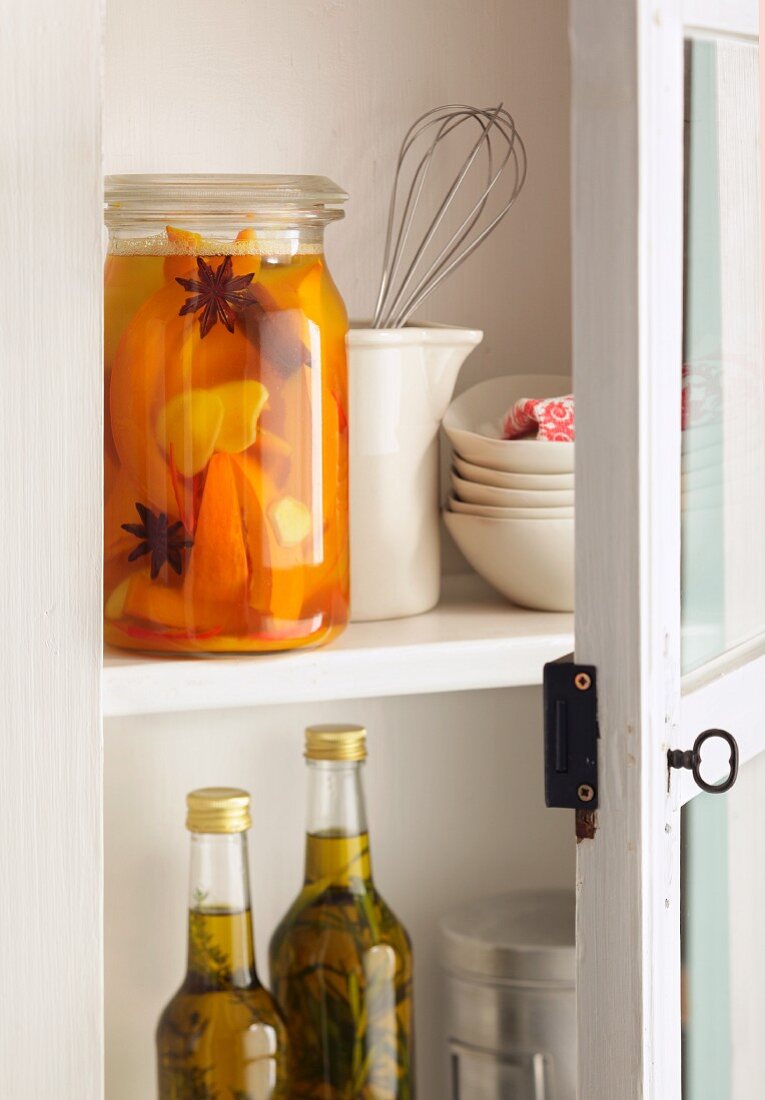 Preserved fruits and kitchen utensils in an open kitchen cupboard