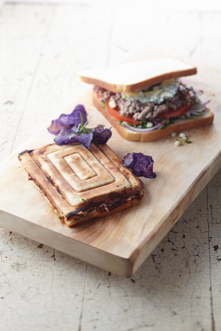 A toasted sandwich filled with minced meat, on a wooden board