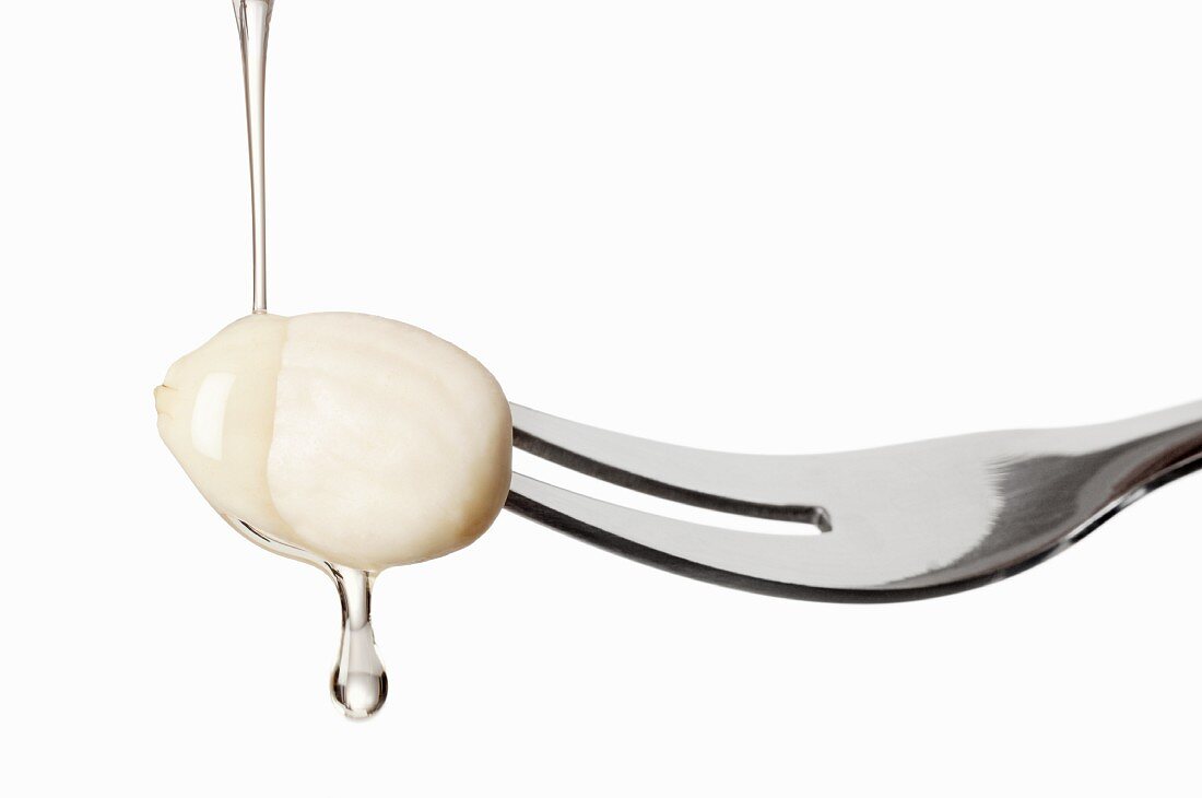 An almond on a fork with droplets of oil