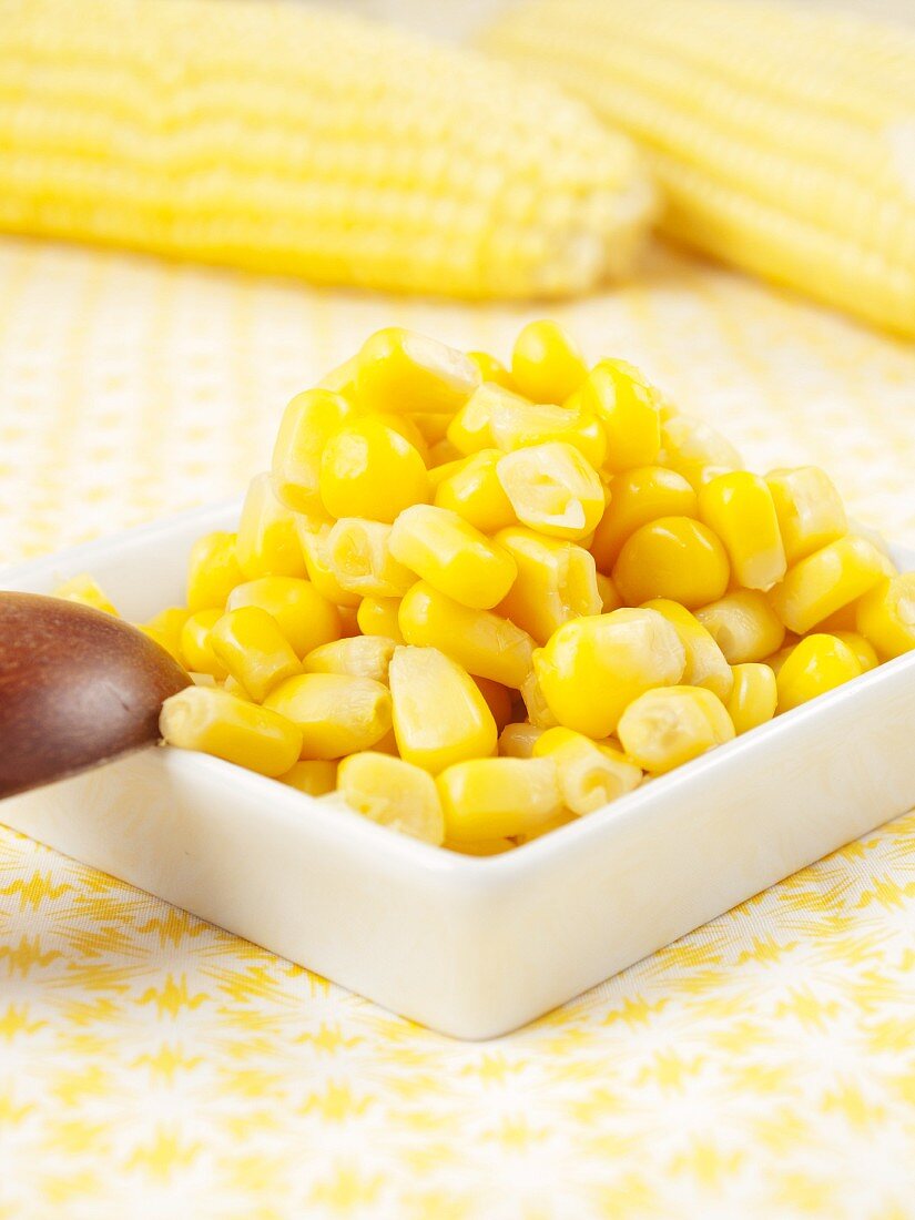 Sweetcorn in a small dish in front of corn cobs