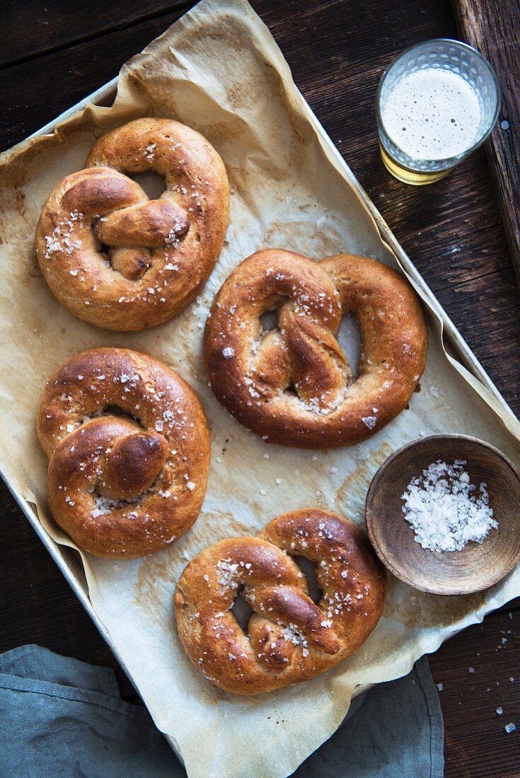 Salted pretzels on a baking tray, and a glass of beer