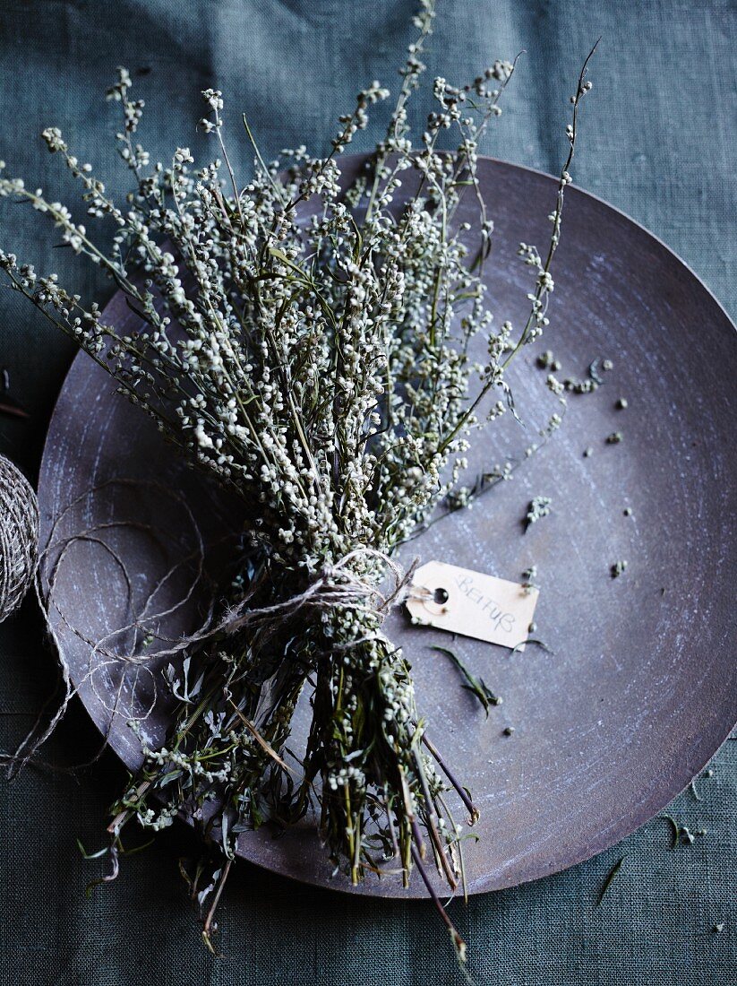 Dried mugwort, tied in a bunch with a label, on a plate