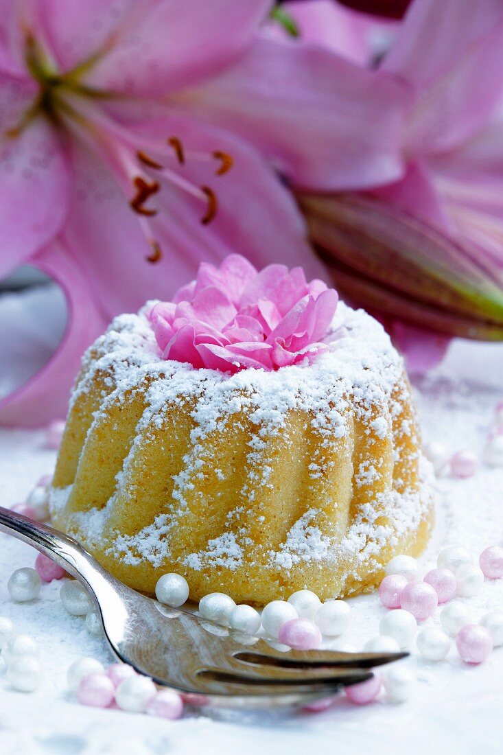 A mini Bundt cake with icing sugar and flower decoration