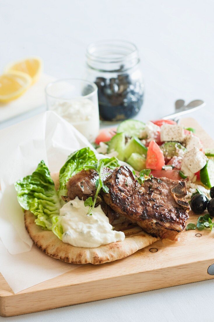 Lamb chop on pita bread, with a Greek salad and tzatziki