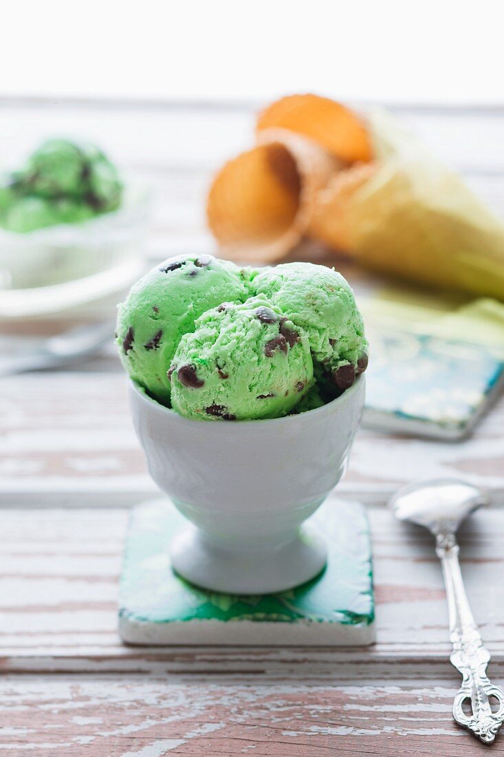 Two Scoops of Mint Chocolate Chip Ice Cream in a Glass Bowl with Mint Garnish