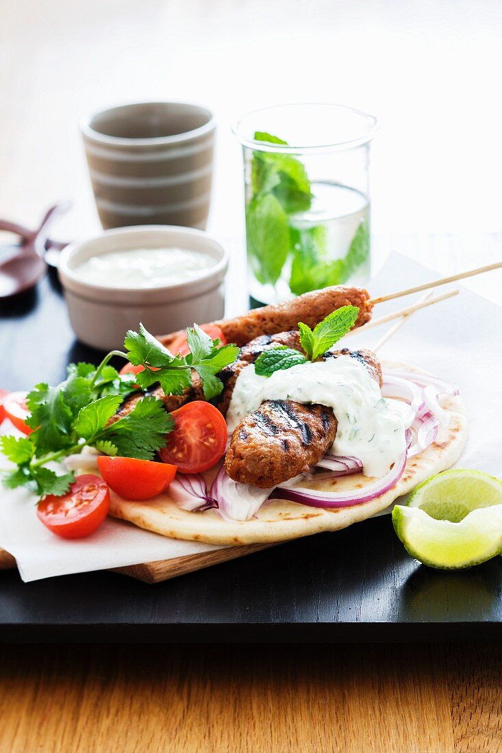 Turkey koftas on a skewer with dip and pita breads