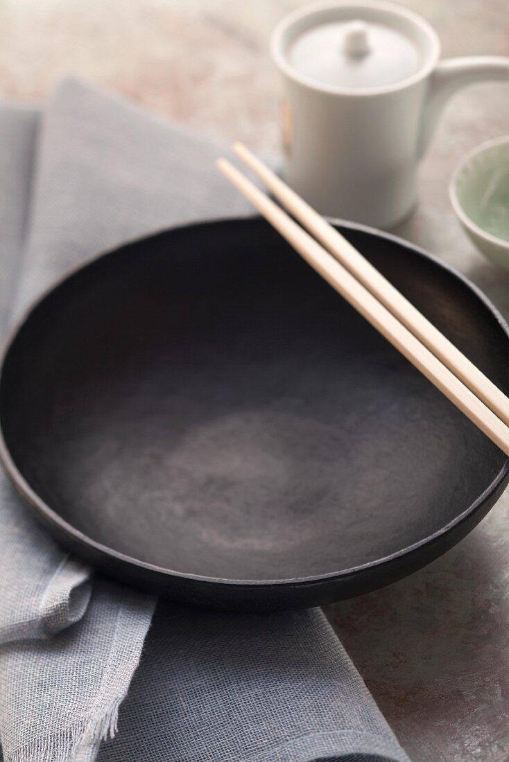 An empty black eating bowl with Asian chopsticks