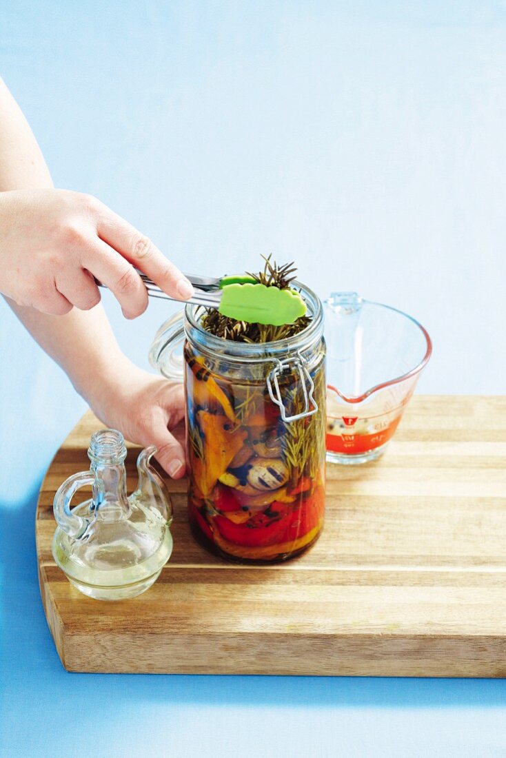 Rosemary being added to preserved peppers