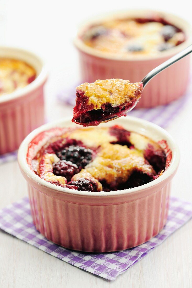 Blackberry clafoutis in ramekins and on a spoon