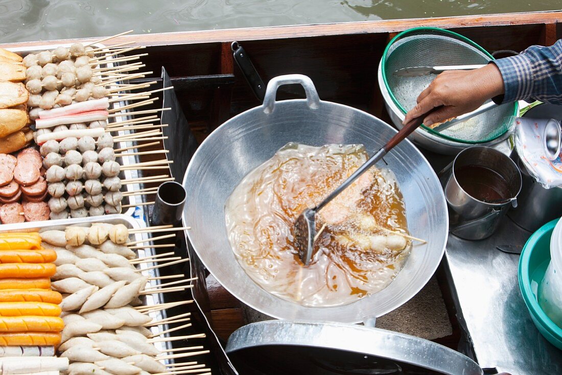 A woman cooking a traditional dish on a boat at the market (Bangkok, Thailand)