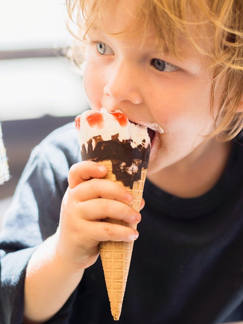 A small boy eating an ice cream cone