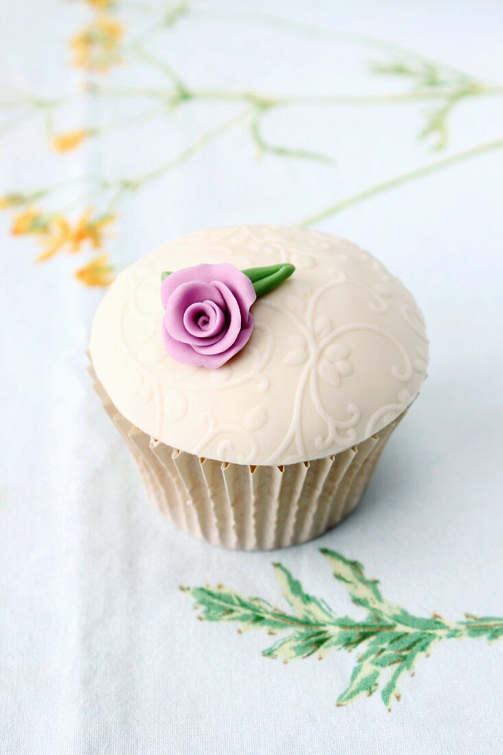 A cupcake with glacé icing and a sugar flower