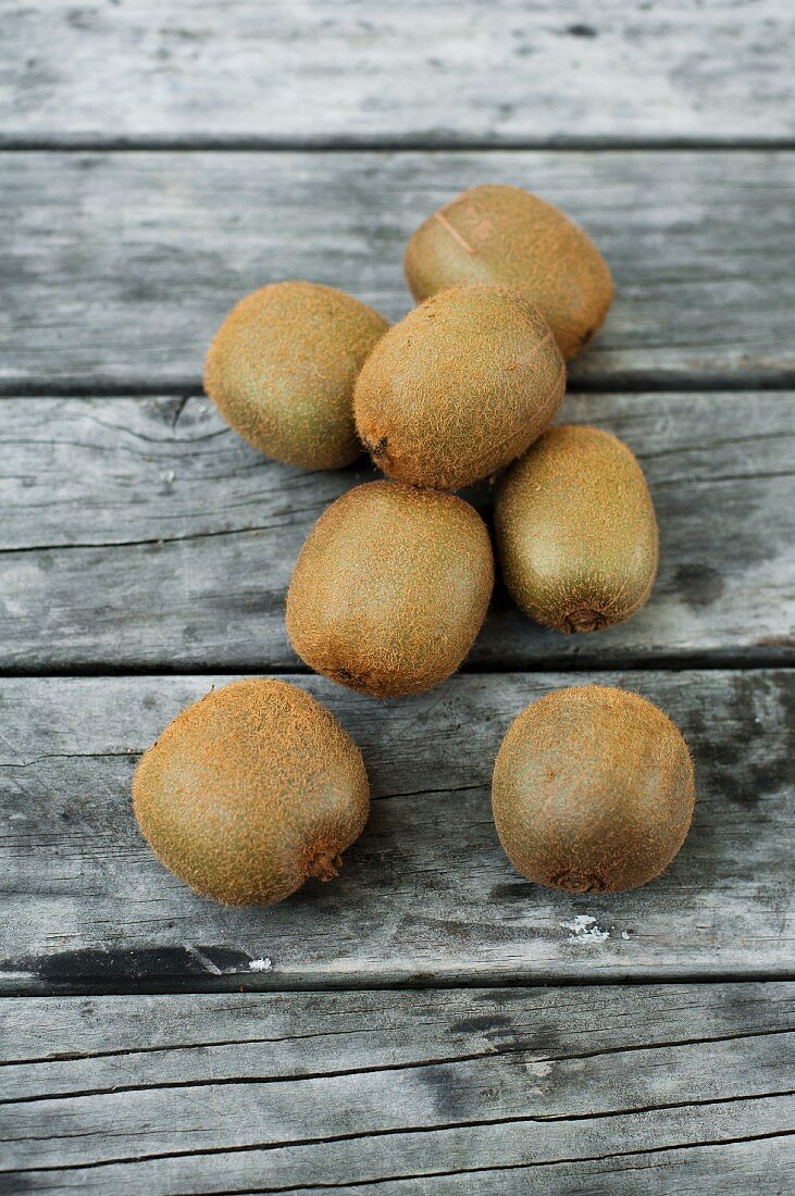 Several kiwi fruit on a wooden surface