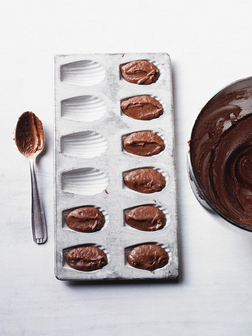 A madeleine tin with chocolate cake mixture