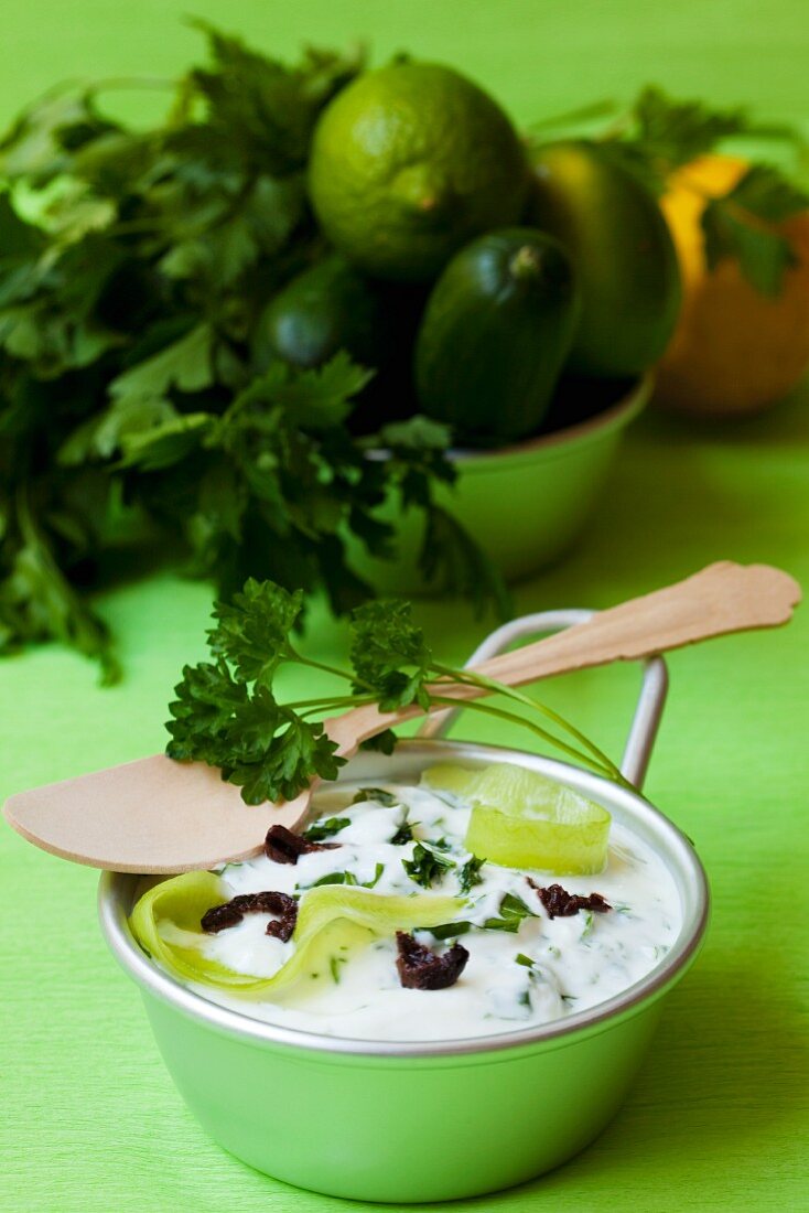A quark dip with cucumber strips, parsley and black olives