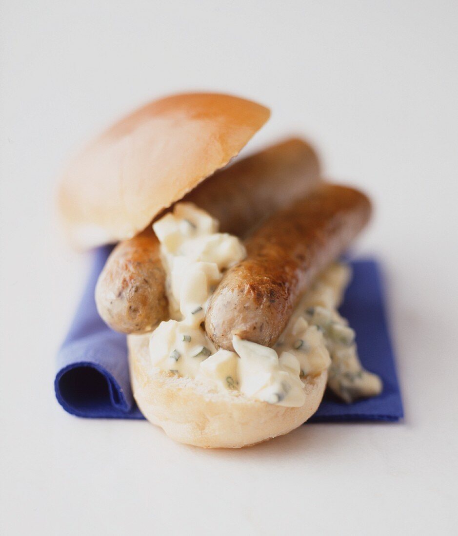 A bread roll with bratwurst sausages and egg salad