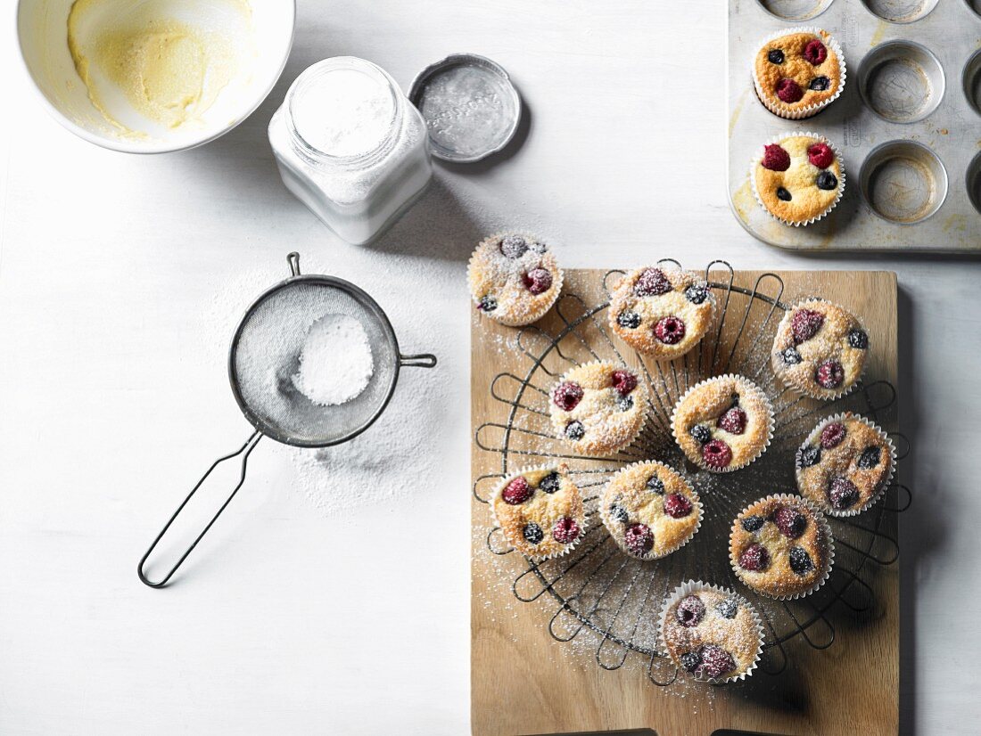 Frisch gebackene Heidelbeer-Himbeer-Muffins mit Puderzucker