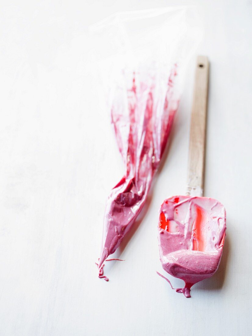 A piping bag and a dough spatula with pink icing