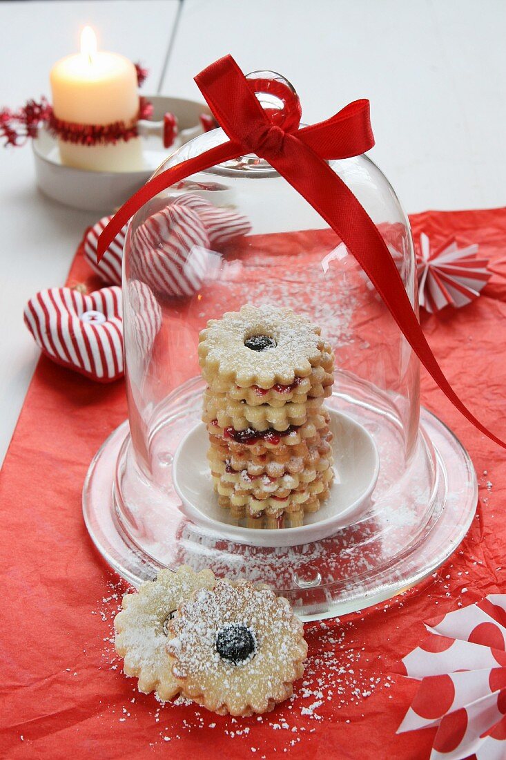 Jam-filled ring biscuits under a glass dome, a fabric heart and a candle