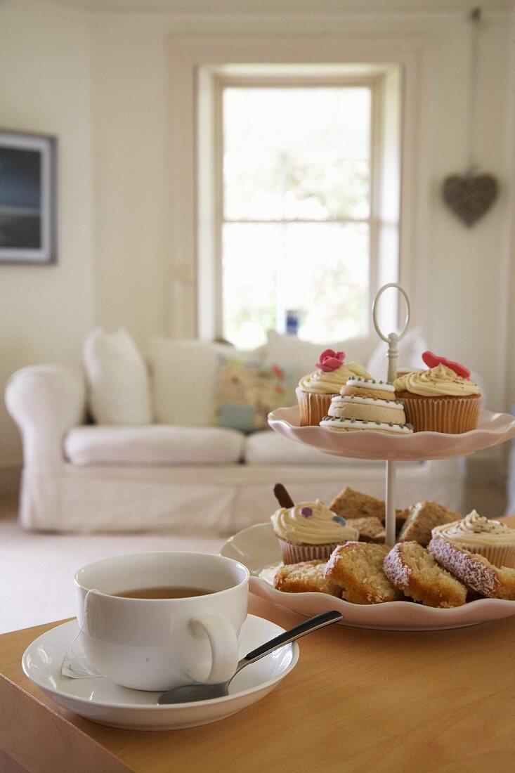 Cup of tea & pastries on cake stand on table in living room