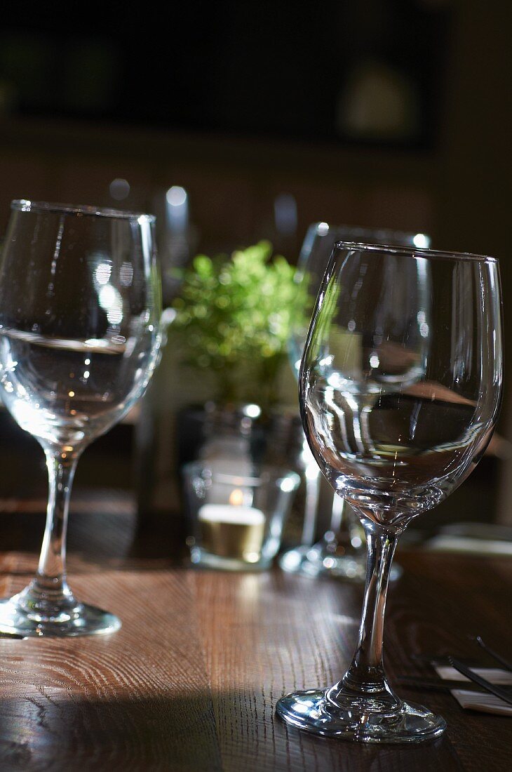 Several empty wine glasses on a wooden table in a restaurant