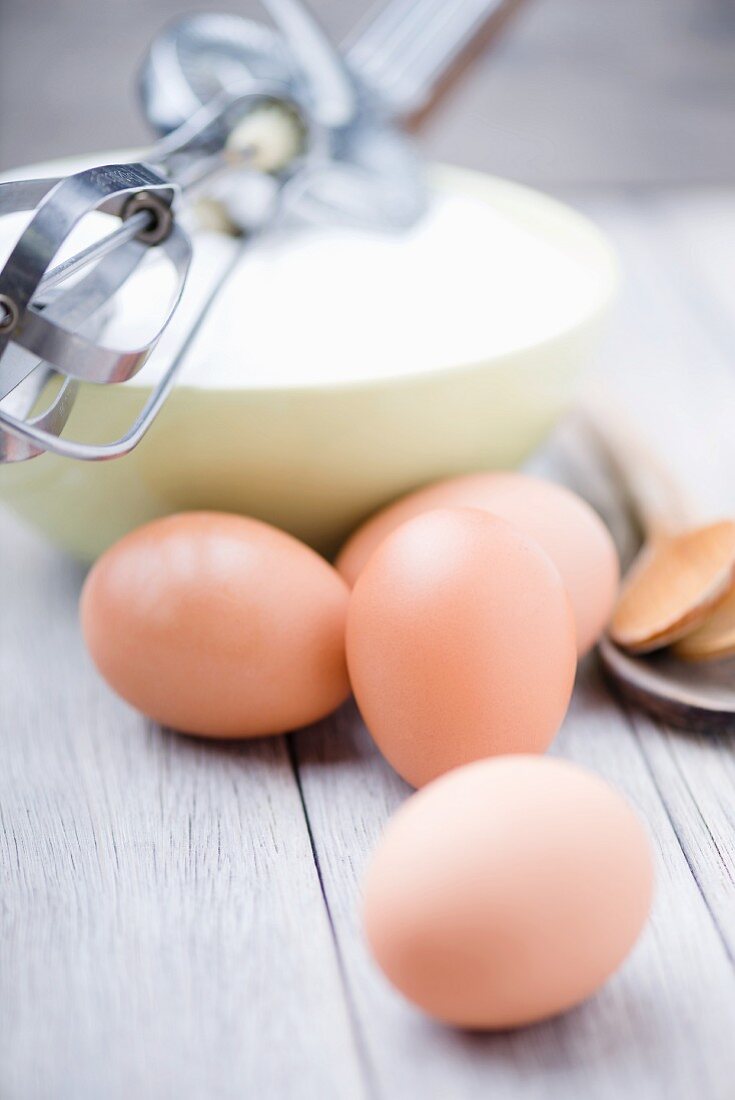 An old rotary hand whisk, eggs and sugar