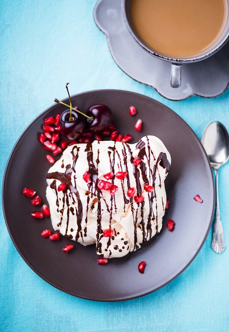 Baisergebäck mit Granatapfelkernen, Kirschen und Schokosauce zum Kaffee