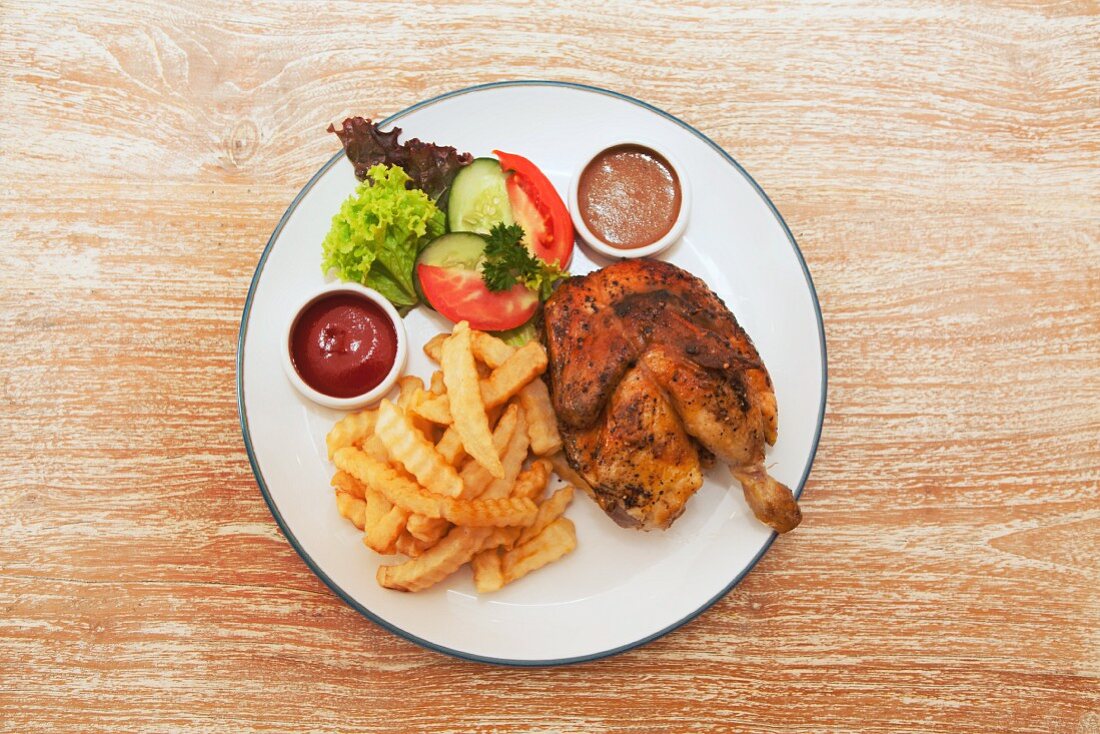 Spicy chicken leg with chips, ketchup and a side salad