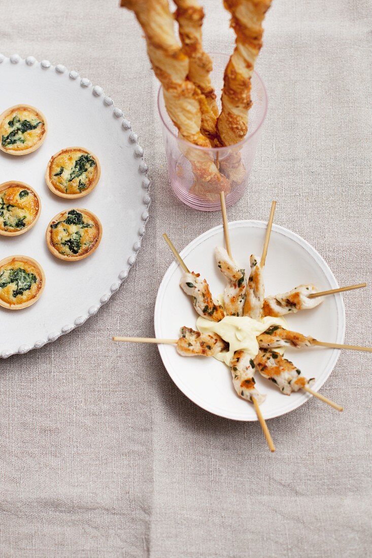 Assorted party snacks (mini spinach quiches, cheese straws, satay skewers)