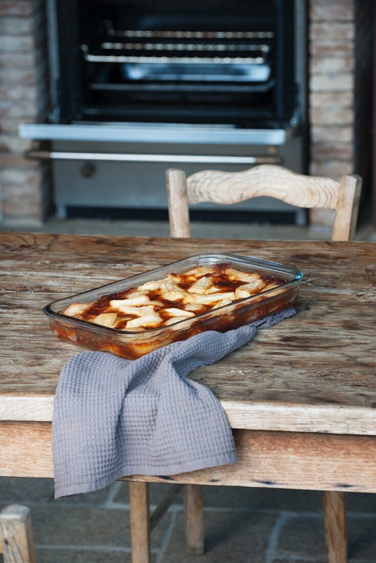 Pear clafoutis in the baking dish on a wooden table in front of the oven