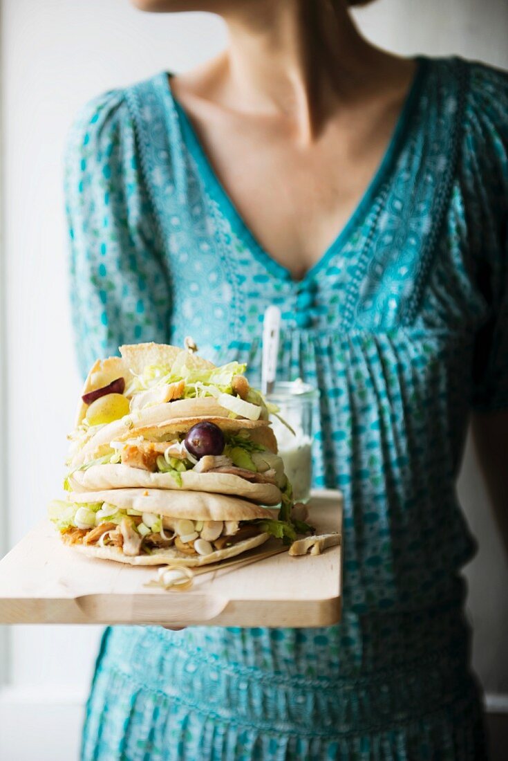 A woman serving pita bread with chicken salad, grapes, and a garlic, tarragon & cheese dressing