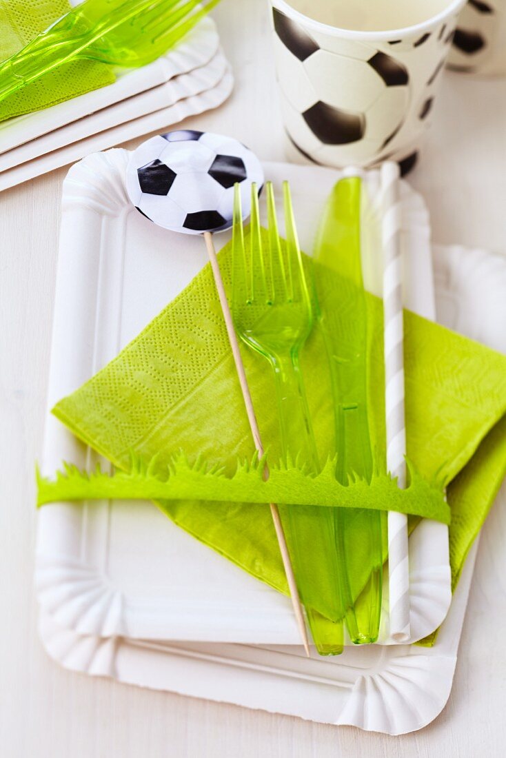 A football-themed party set consisting of paper plates, cutlery, napkins, a straw and a toothpick flag