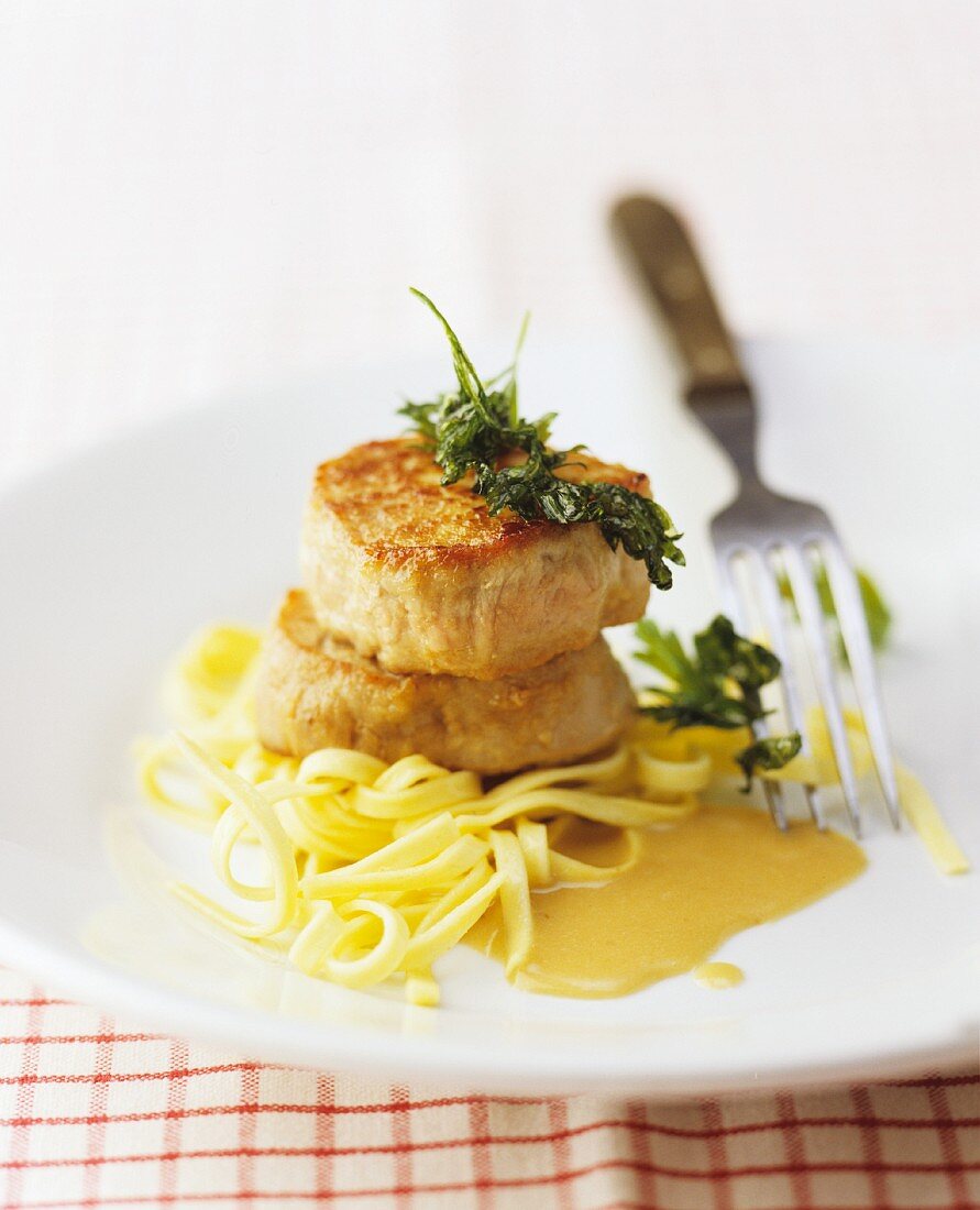 Pork medallions with a creamy sauce on ribbon pasta