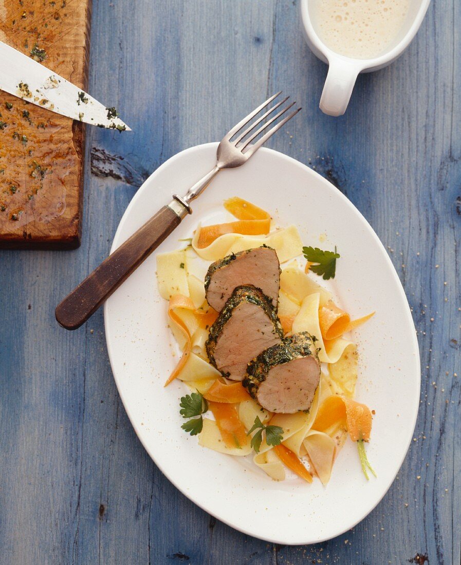 Veal fillet with a herb crust on ribbon pasta and carrot strips