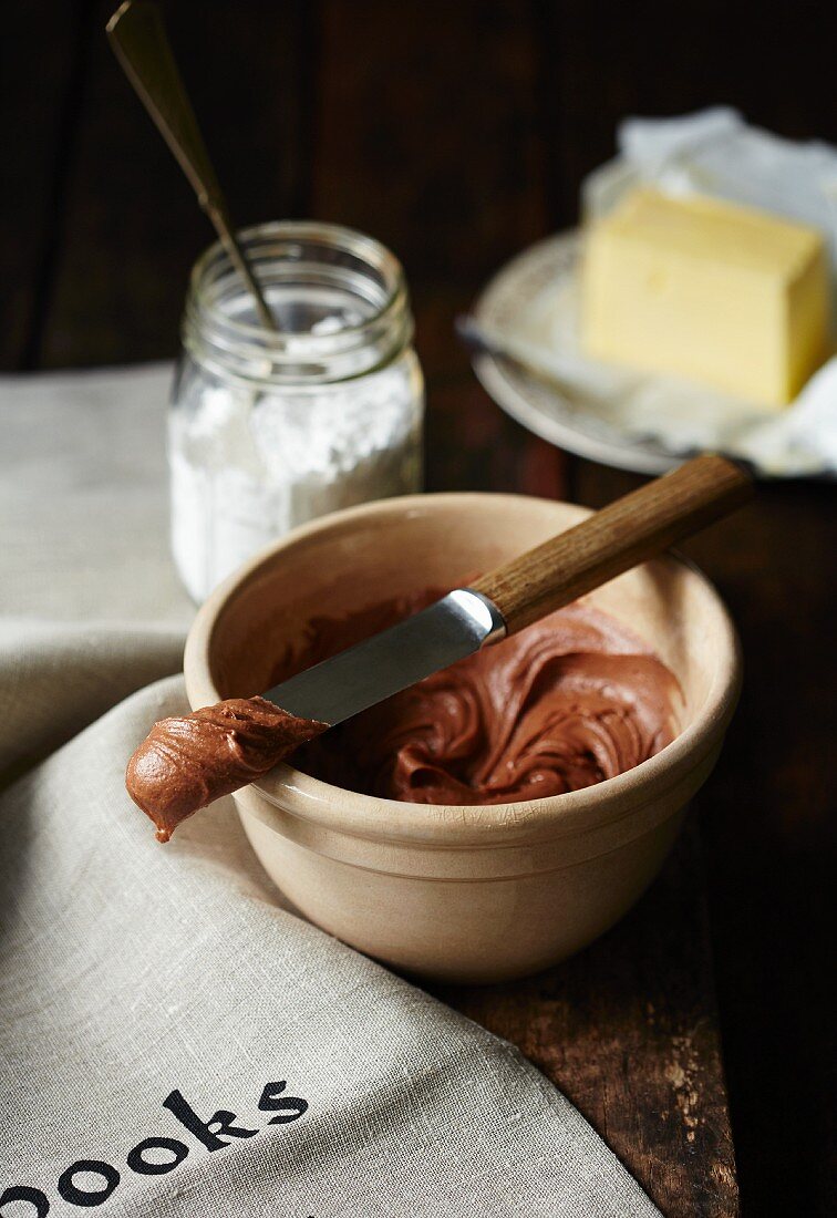 Chocolate buttercream in a bowl in front of ingredients