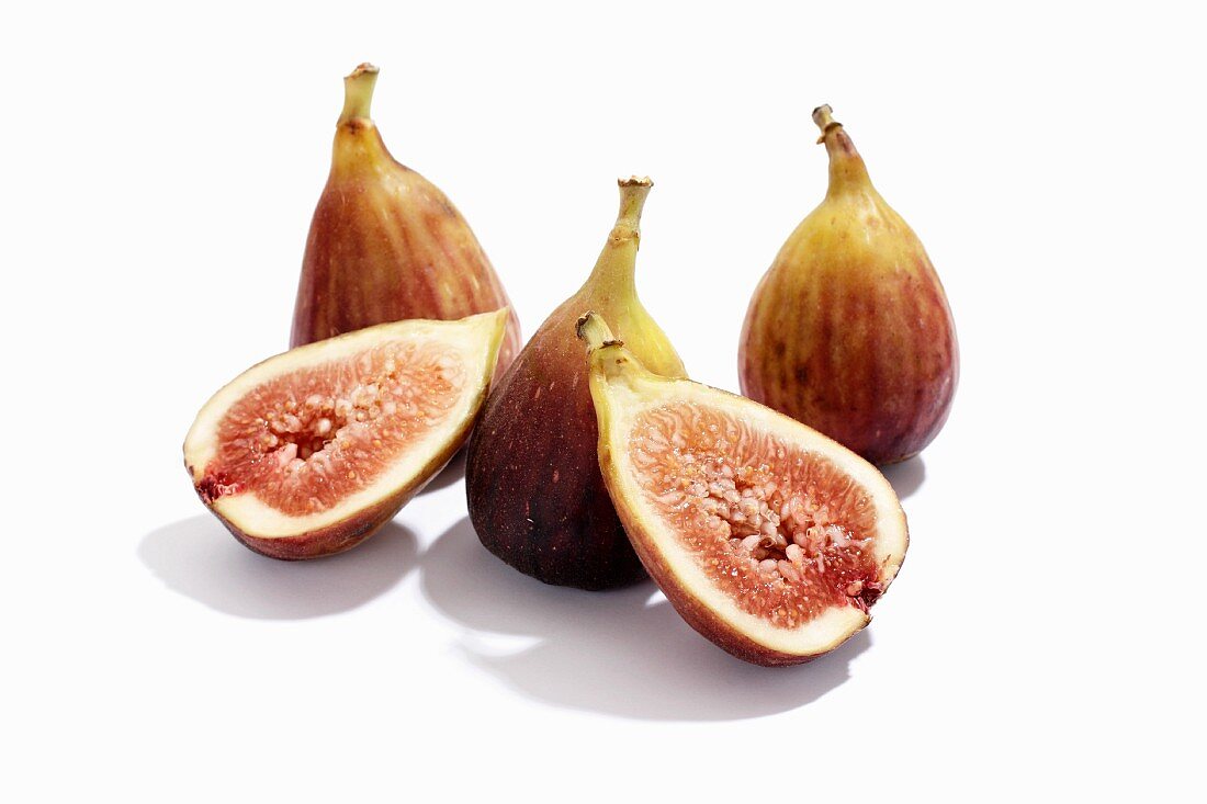 Fresh figs, whole and halved, against a white background