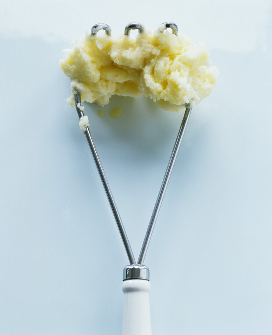 A potato masher with mashed potato