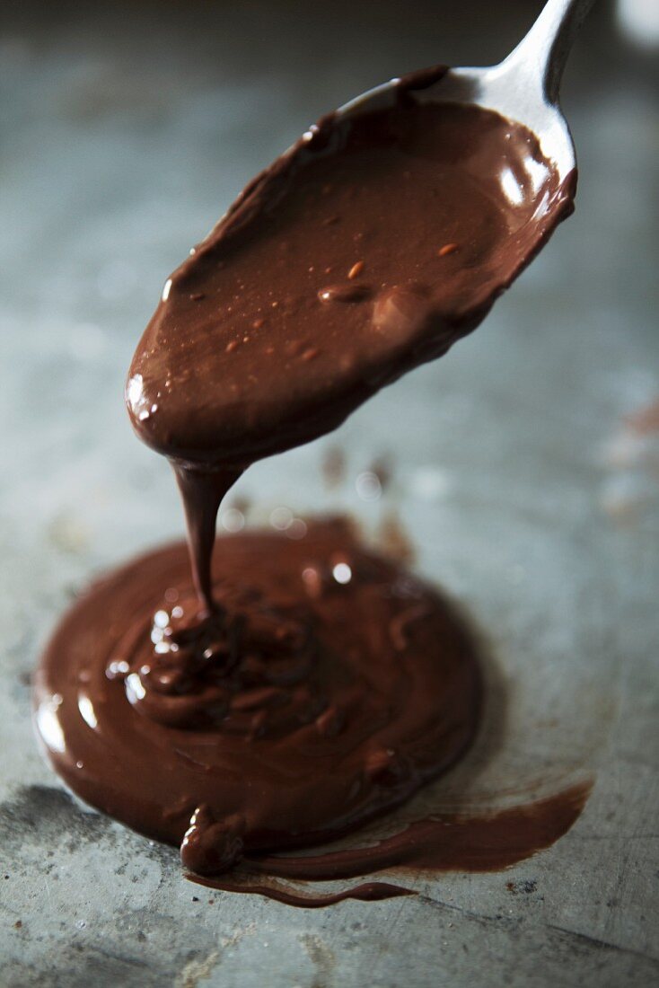 Flüssige Schokolade läuft von Löffel auf Backblech