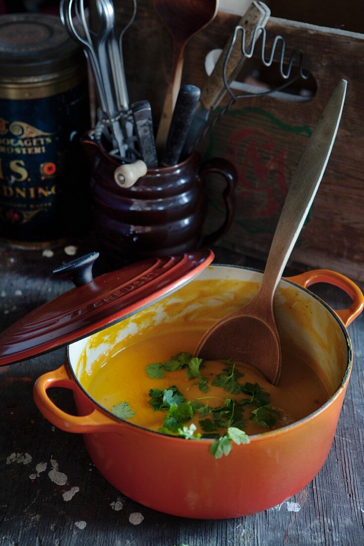 Carrot soup with mustard and coriander in a pot