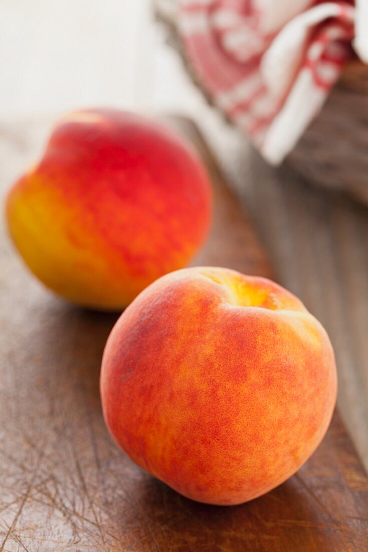 Two whole peaches on a wooden board