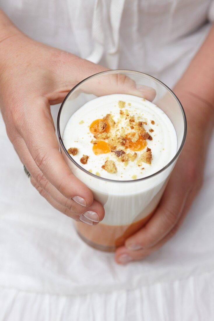 A woman holding a glass of apricot dessert