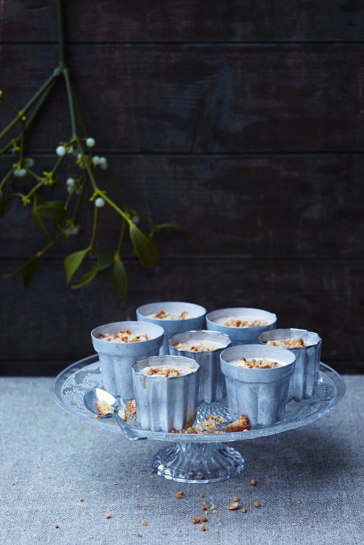Parfaits in front of a wooden wall with a sprig of mistletoe