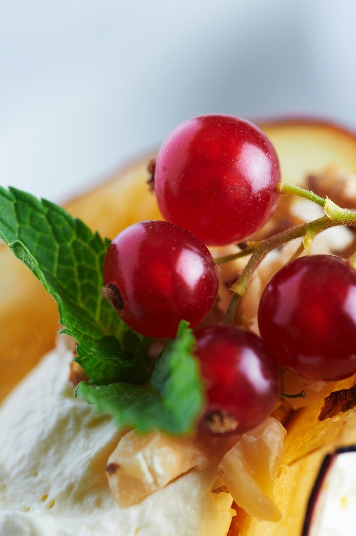 Rote Johannisbeeren und Minzeblatt auf Eiscreme (Close Up)